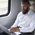 Pracownik w delegacji służbowej pracuje na laptopie w pociągu