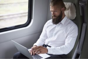 Pracownik w delegacji służbowej pracuje na laptopie w pociągu